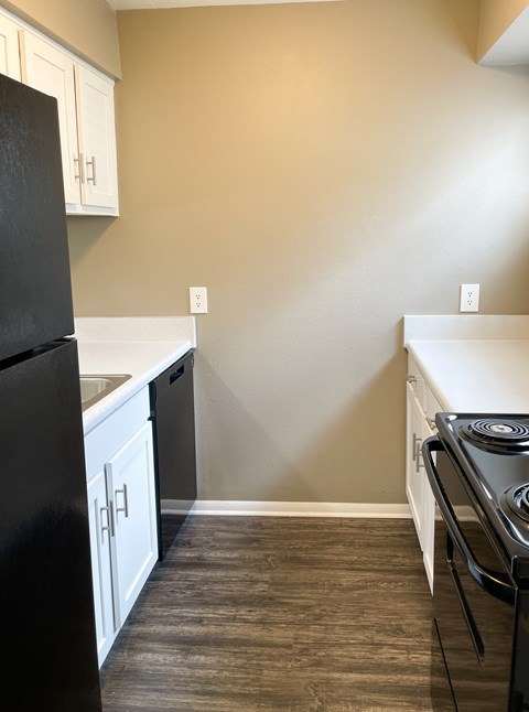 A kitchen with a black fridge and stove top oven.