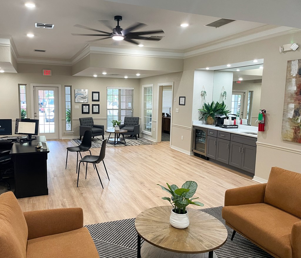 A living room with a ceiling fan and a table with a plant on it.