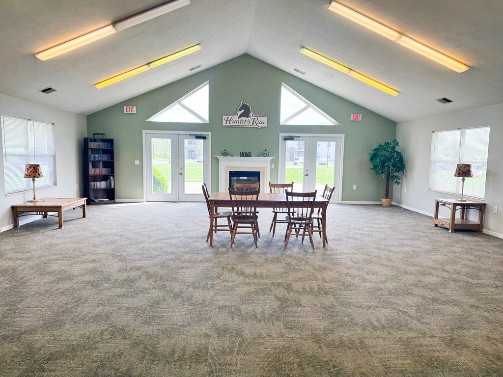 A room with a carpeted floor and a dining table set up with chairs.
