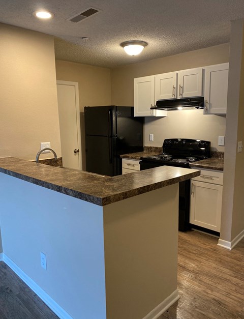 a kitchen with a counter top and a black refrigerator