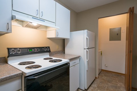 A kitchen with a white stove and refrigerator.