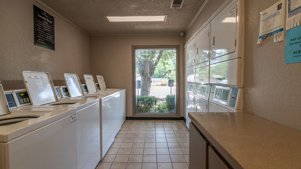a laundry room with a door to a yard and a counter with washing machines and