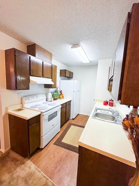 A kitchen with white appliances and brown cabininets.