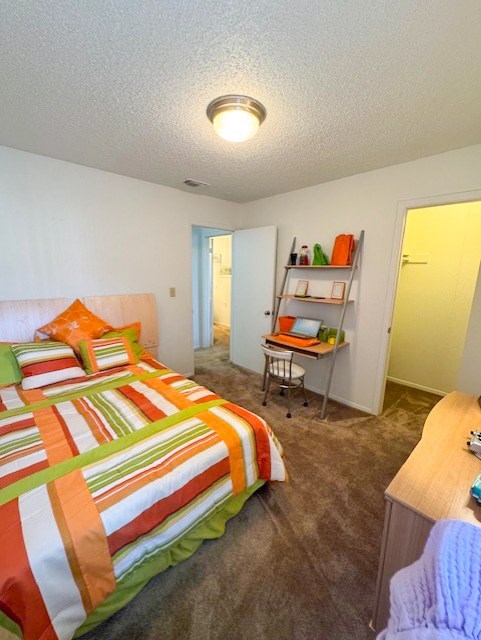 A bedroom with a bed, desk, and chair.