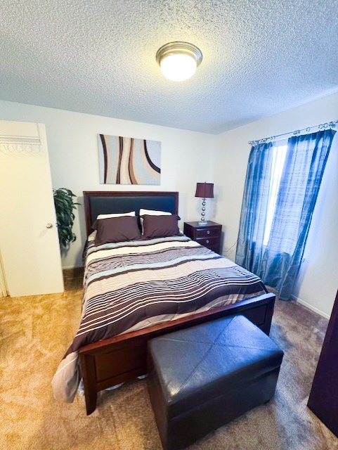 A bedroom with a bed, nightstand, and chair.