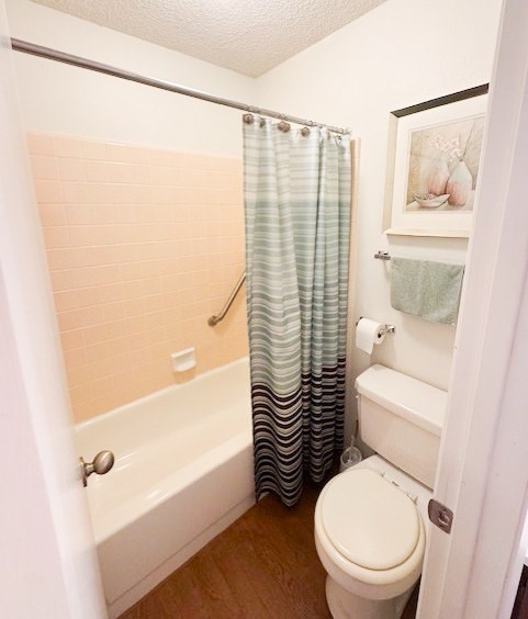 A small bathroom with a toilet, a bathtub, and a shower curtain.