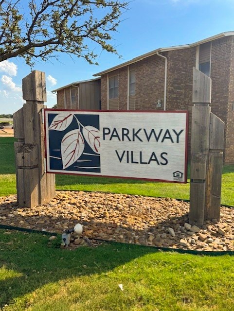 A sign for Parkway Villas in front of a brick building.