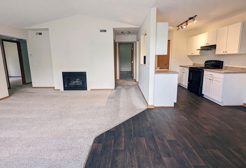 a renovated living room and kitchen with white cabinets and wood floors
