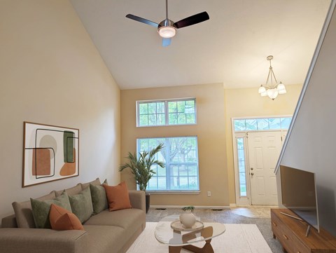 A living room with a grey couch and a ceiling fan.
