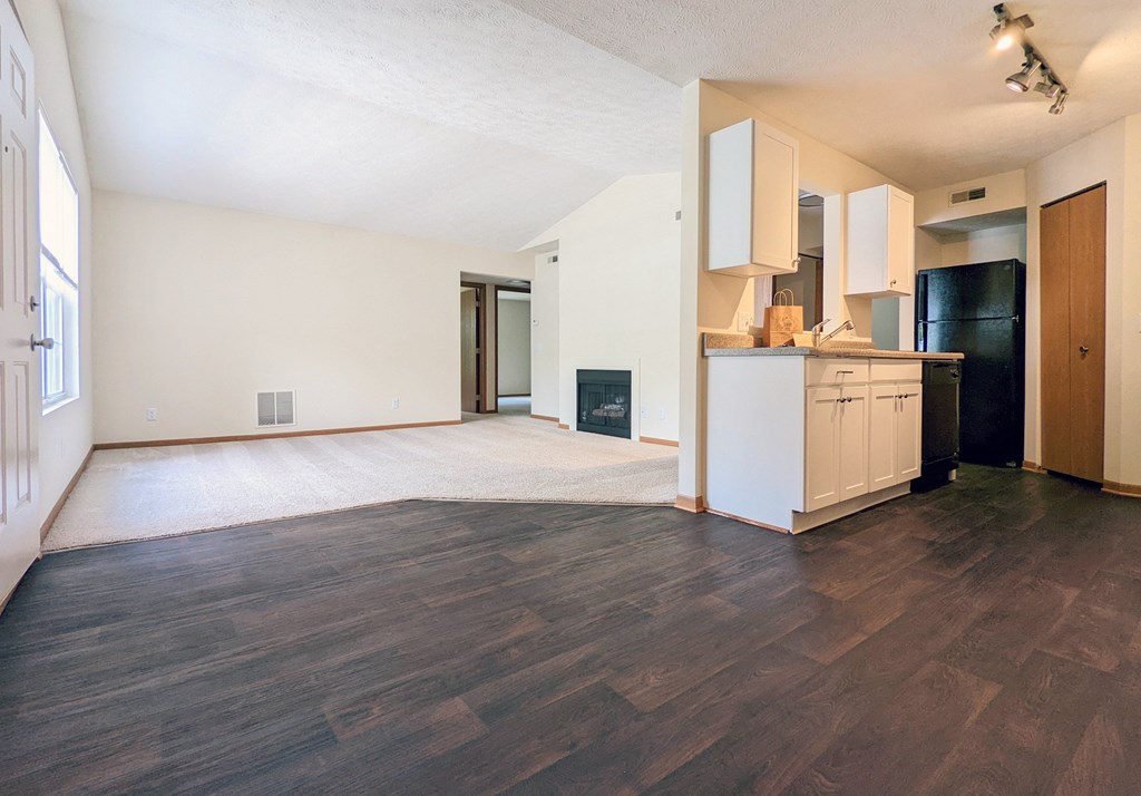the living room and kitchen of an empty apartment with wood flooring