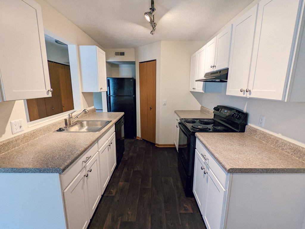an empty kitchen with white cabinets and granite counter tops