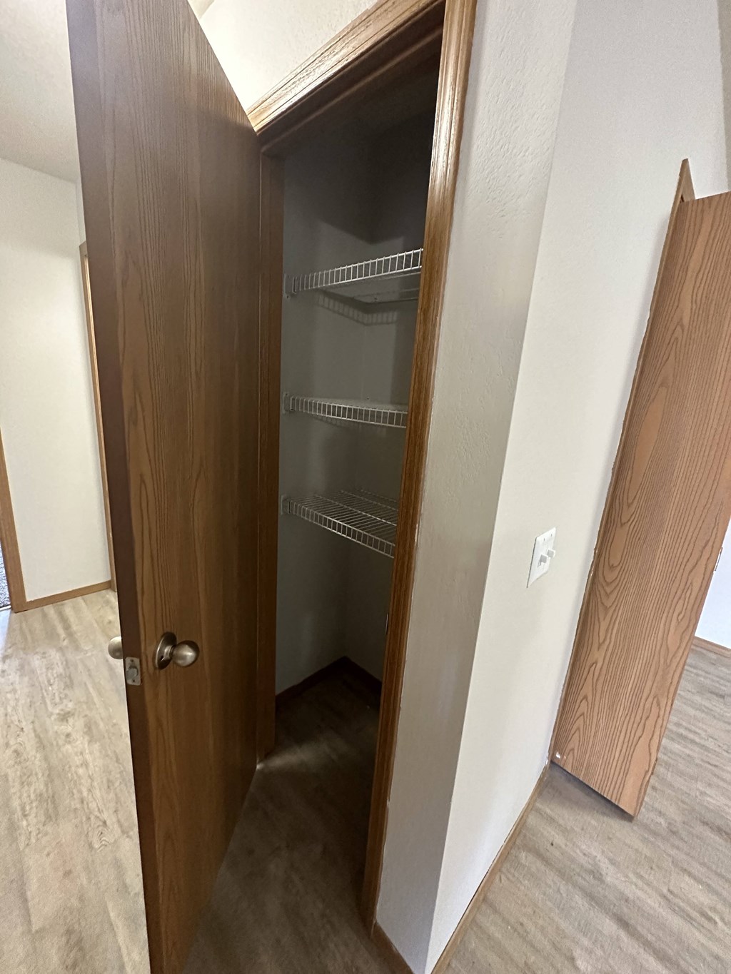 a walk in closet in a bedroom with a wooden door and white walls