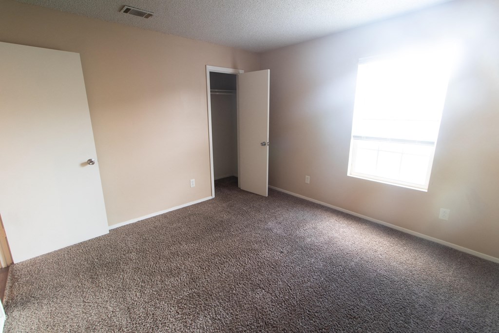 an empty room with carpet and a door to a closet