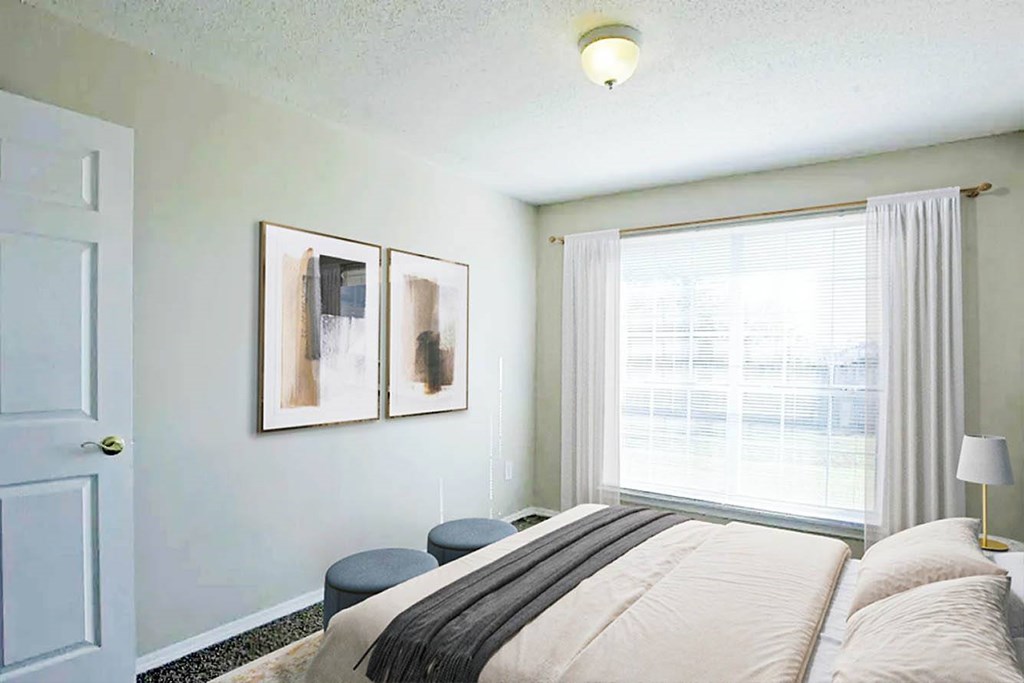 A bedroom with a large bed and two framed pictures on the wall.