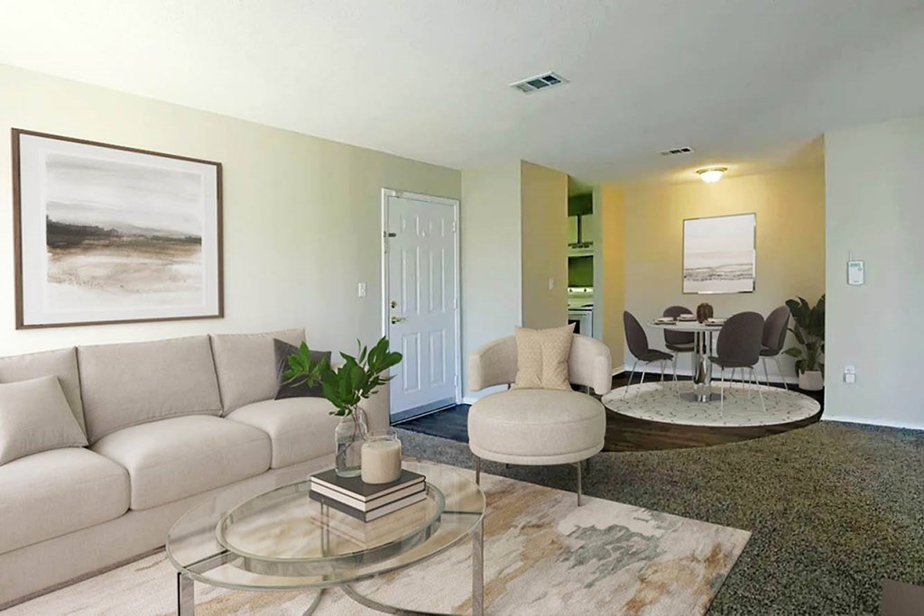 A living room with a white couch, a glass coffee table, and a painting on the wall.