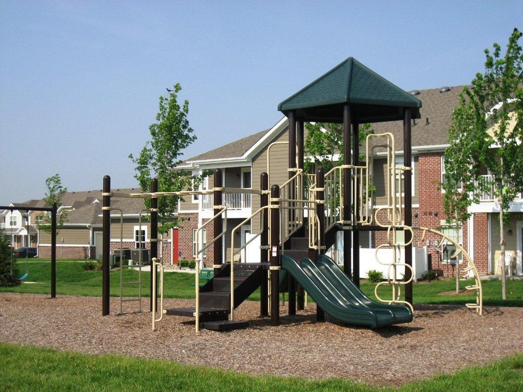 A playground with a green slide and a green roofed pavilion.
