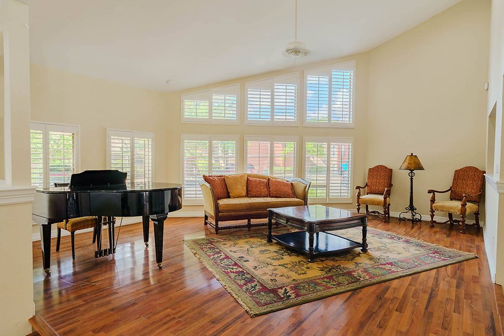 A living room with a piano, couch, and chairs.