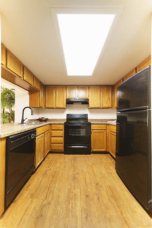 A kitchen with black appliances and wooden cabinets.