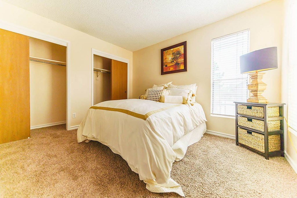 A bedroom with a bed, nightstand, and two closets.