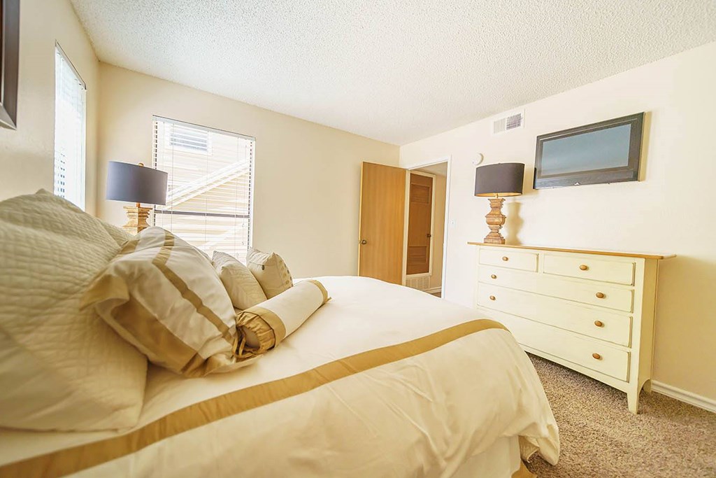 A bedroom with a bed, nightstand, and a television.