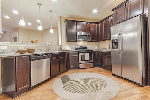 A modern kitchen with dark wood cabinets and stainless steel appliances.