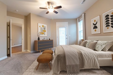 A bedroom with a bed, a chair, and a ceiling fan.