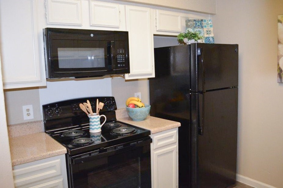 A black stove top oven and black refrigerator in a kitchen.