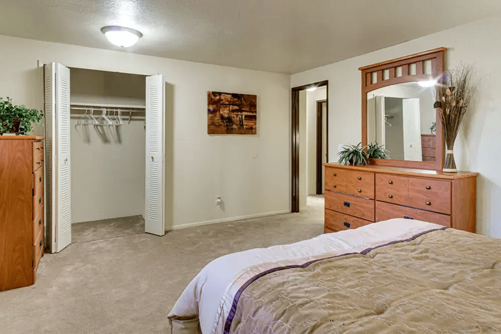 A bedroom with a bed, dresser, and mirror.