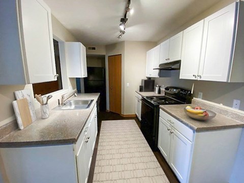 A kitchen with white cabinets and a black stove top oven.