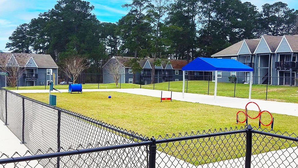 A playground with a blue canopy and a fence in the foreground.