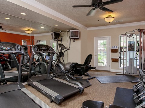 A home gym with a treadmill, elliptical machines, and other exercise equipment.