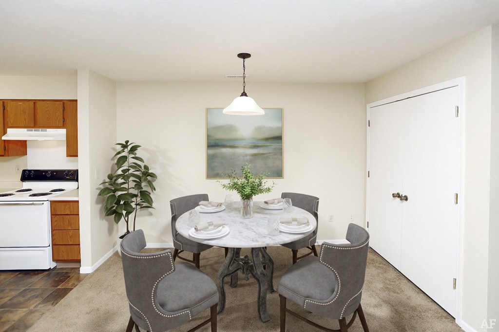 a dining area with a table and chairs and a kitchen in the background