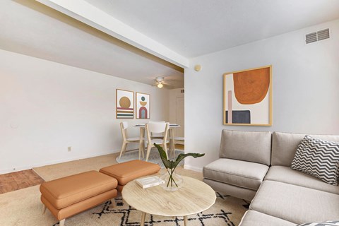 A living room with a couch, chair, and a table with a plant on it.