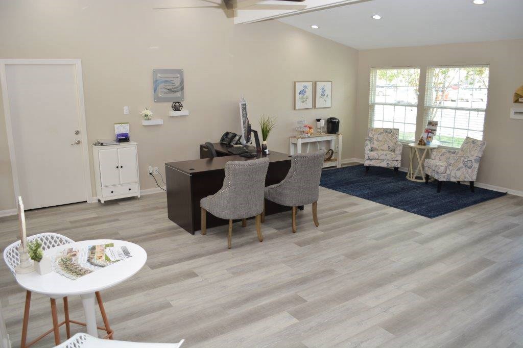 A living room with a white table and grey chairs.