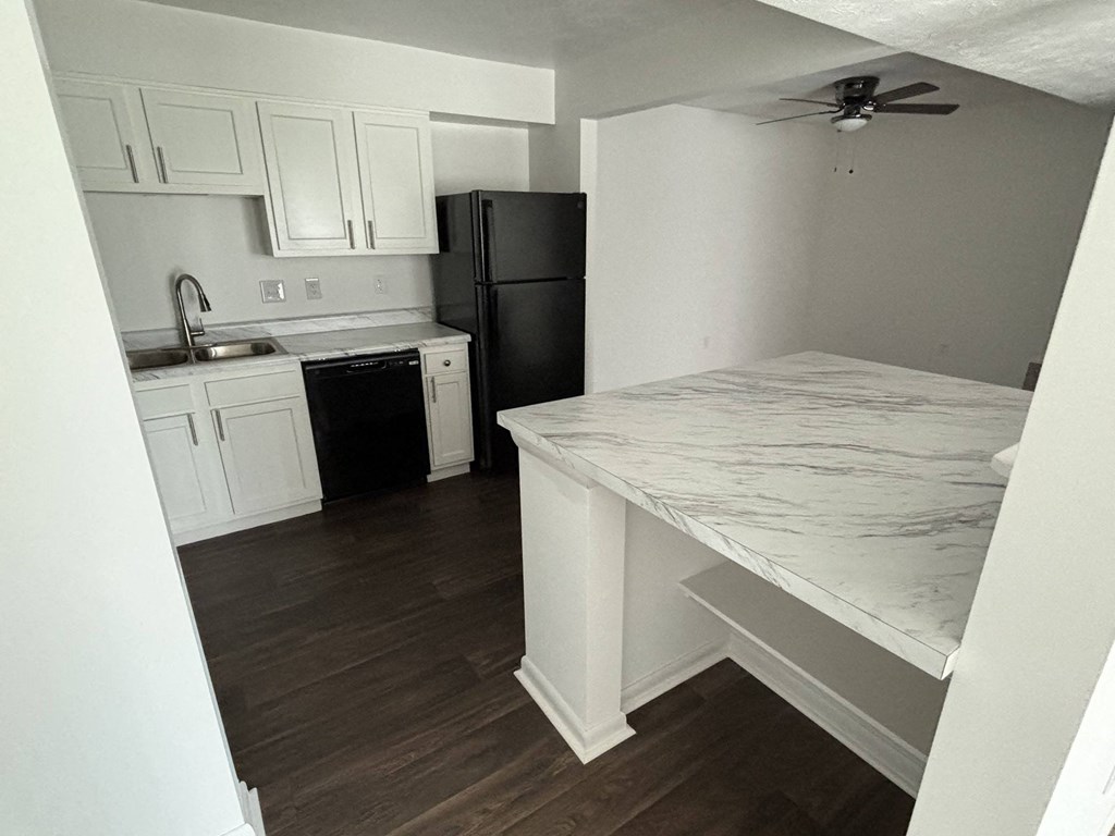 a kitchen with white cabinets and a marble counter top