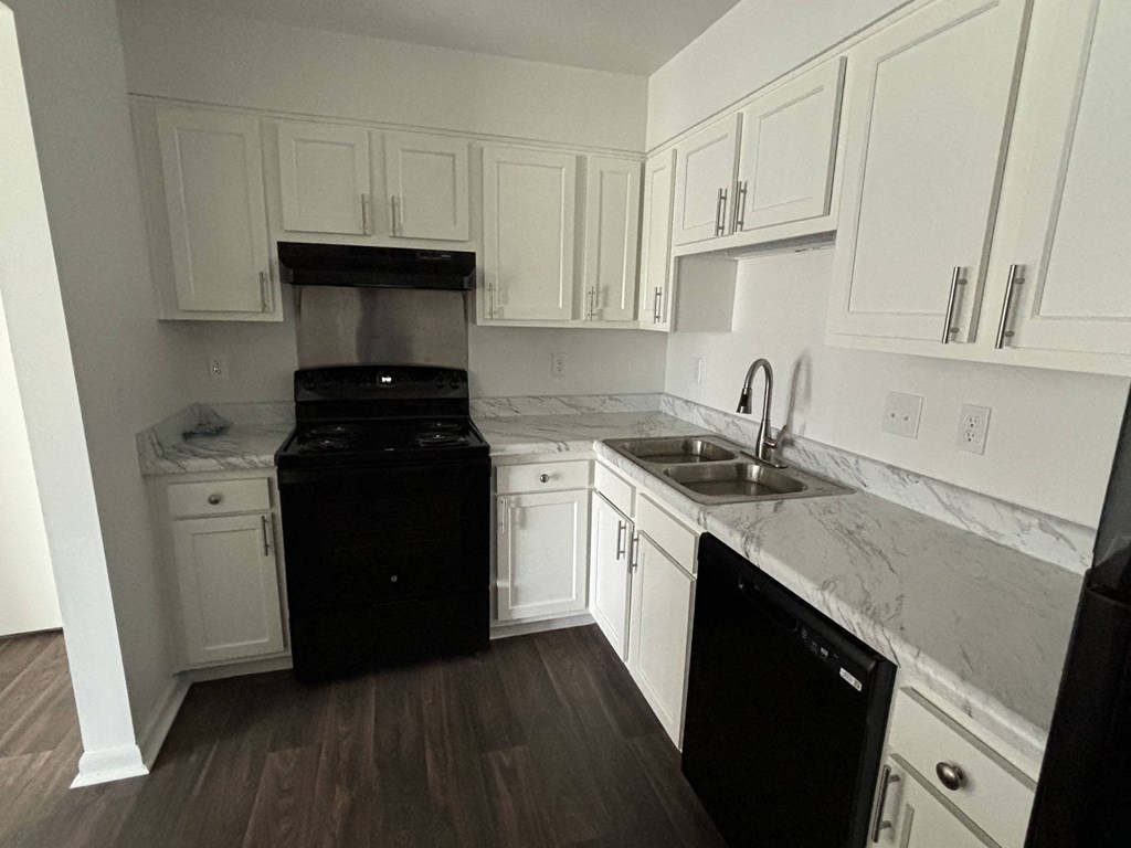 a kitchen with white cabinets and a black stove and sink