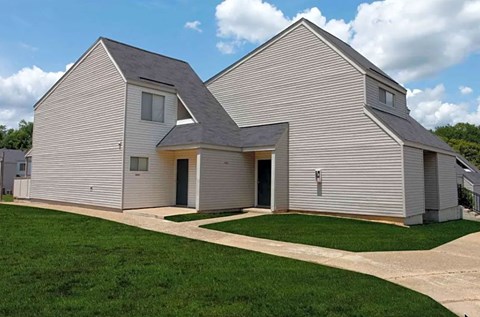 a white house with a gray roof and a lawn