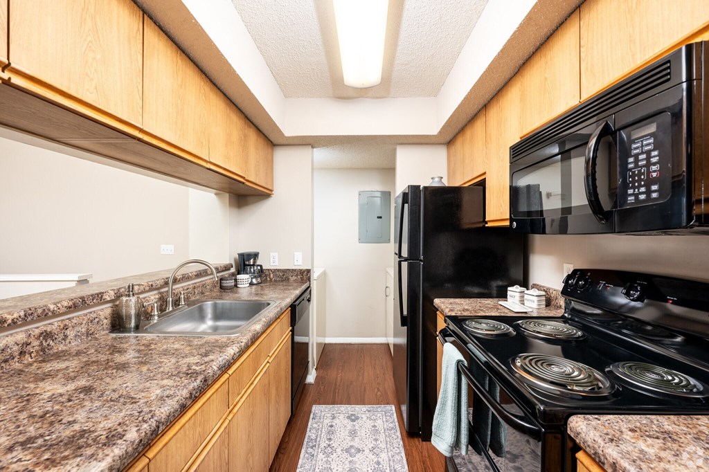 A kitchen with granite countertops and a black stove.