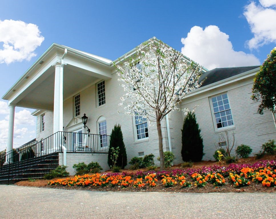 a white house with a flower garden in front of it