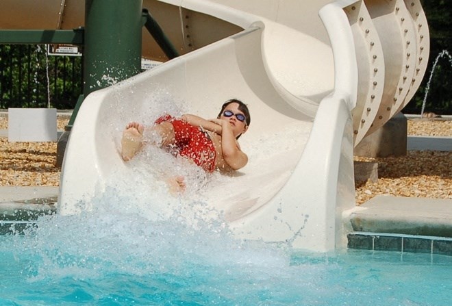 a young boy sliding down a slide in a pool on a water slide
