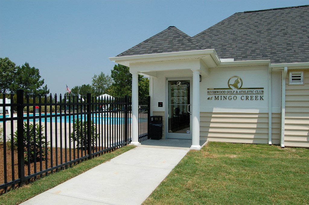 a white building with a fence and a door to a gated entrance