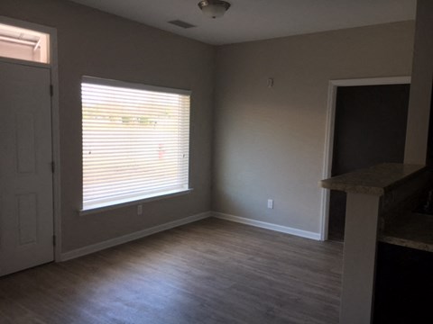an empty living room with wood floors and a window