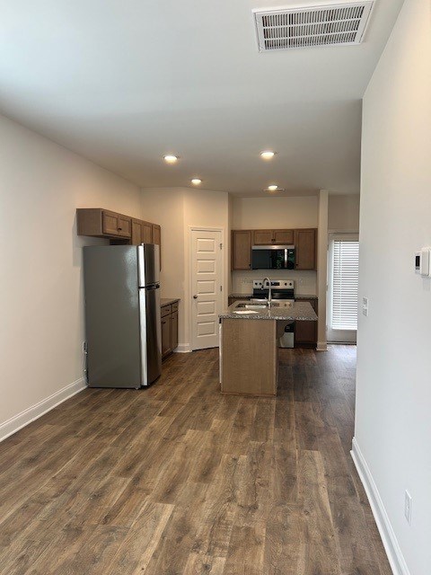A kitchen with a refrigerator, microwave, and oven.