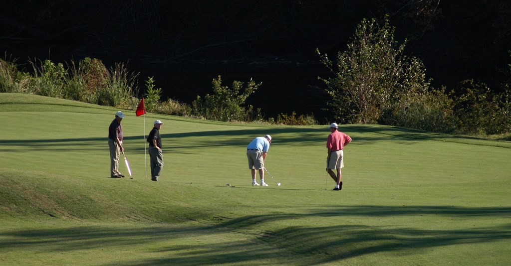a group of men playing golf on a golf course