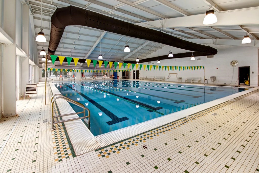 a swimming pool at a gym with a blue pool and white tiles