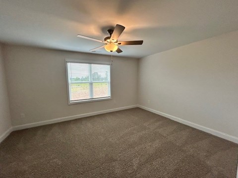 A room with a ceiling fan and a window.