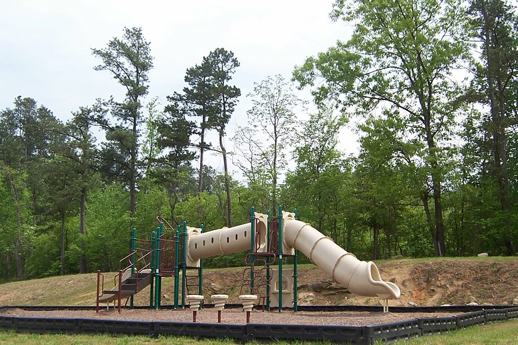a playground with a slide and chairs in a park