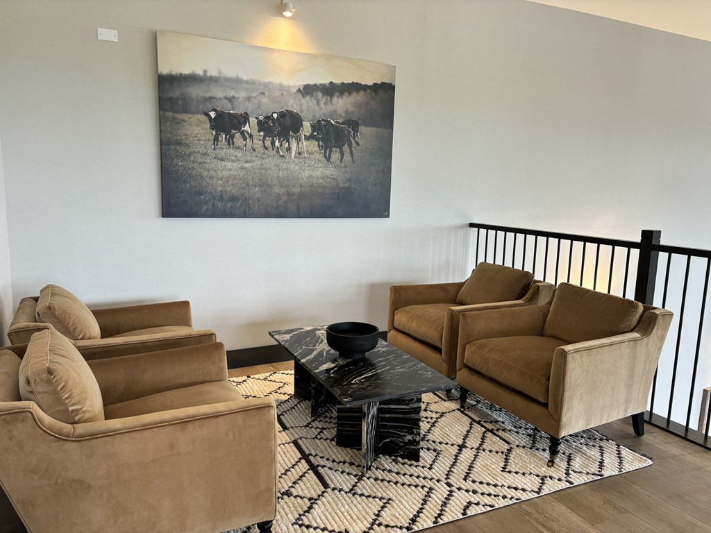 a living room with two brown couches and a painting of cows