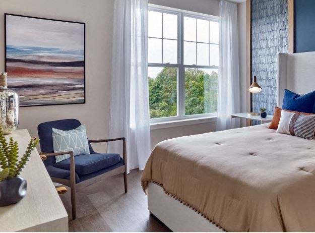 a bedroom with a large bed and a chair in front of a window