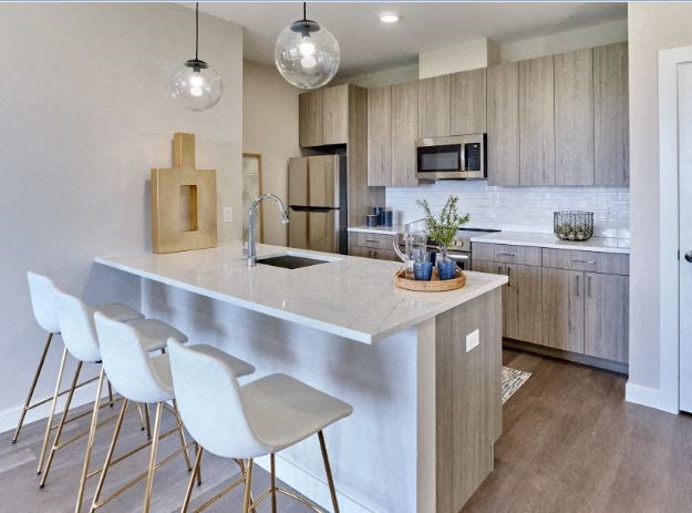 a kitchen with a large island and three white chairs